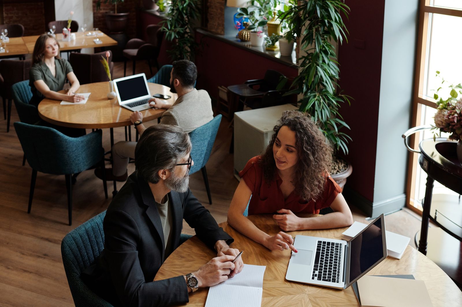 Business owners discussing growth plans over laptops in a cafe